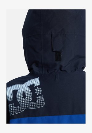 Námořnická kapucňová bunda s modrými akcenty, na zadní straně s velkým bílým logem a designem hvězdy. Vyrobeno z hladkého, povětrnostně odolného materiálu.