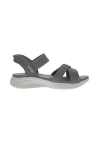 Sandal gris con tiras cruzadas y un acabado texturizado. Suela suave y acolchada en gris claro. Presenta tiras ajustables para un ajuste seguro.