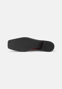 Semelle de chaussure en caoutchouc noir avec une texture lisse, de forme rectangulaire et un léger soutien de la voûte plantaire. Présente un accent surélevé près du talon.