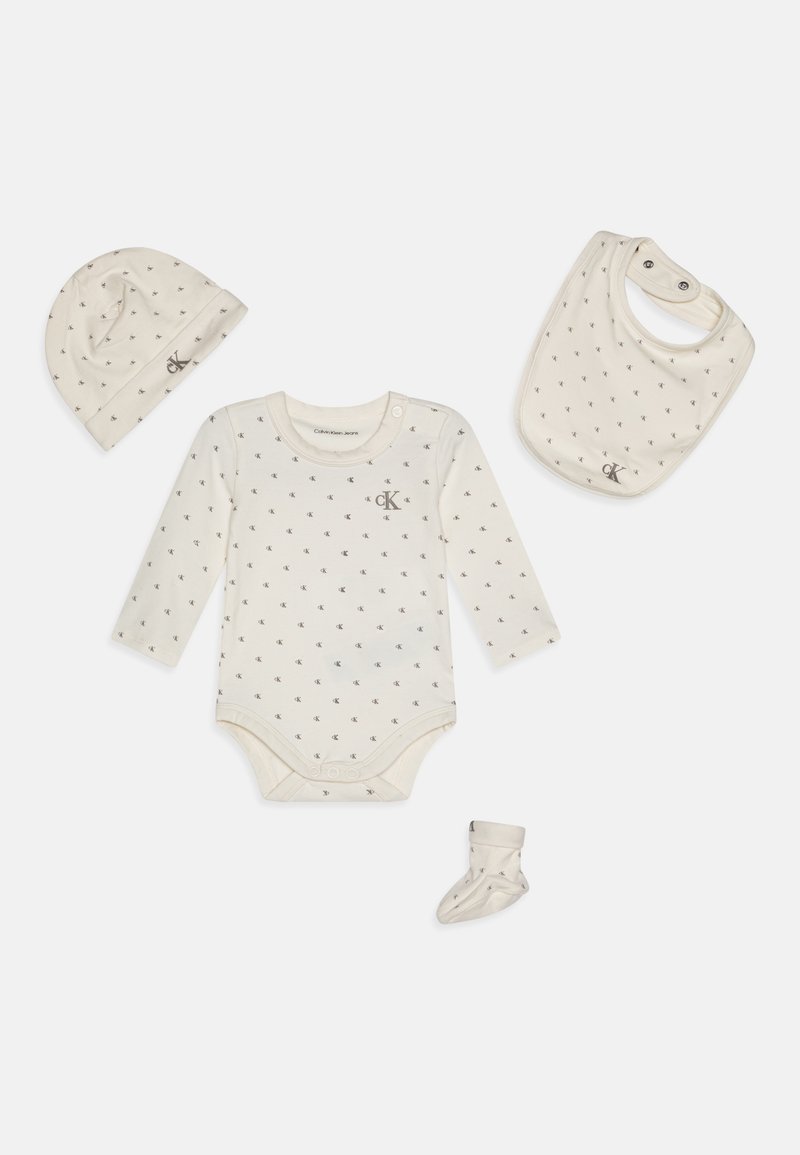 Kūdikių drabužių rinkinys iš medvilnės susideda iš bodžio, skrybėlės, prijuostės ir kojinių. Pagrindas yra kreminės spalvos su pilku raštu ir CK logotipu. Minkštas ir lengvas.