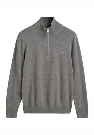 Grijze gebreide trui met een hoge kraag en een kwart ritssluiting. Heeft ribgebreide manchetten en onderrand, samen met een klein geborduurd logo op de borst.