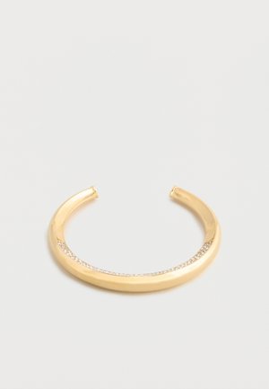 Gold open cuff bracelet with a smooth surface and a curved row of small embedded crystals along the outer edge.
