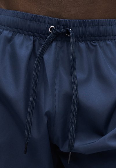 Σορτς με ελαστική ζώνη στη μέση σε ναυτικό μπλε χρώμα και πλεκτό κορδόνι σε ναυτικό μπλε, δεμένο κόμπο στο κέντρο μπροστά.