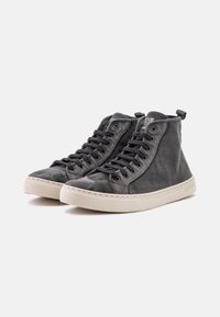 Zapatillas altas de lona gris oscuro con cordones negros, suela de goma blanca y un lazo en la parte posterior para facilitar el calzado.