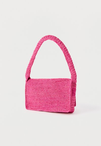 Sac à main rectangulaire en crochet rose avec une large poignée, posé verticalement sur un fond clair uni.