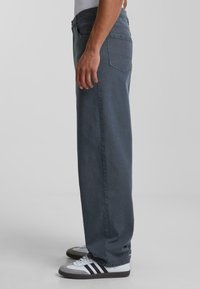 Donkergrijze recht-pas jeans van denim, met een klassieke vijf-pocket design en een gladde textuur. Draag met witte en grijze sneakers.