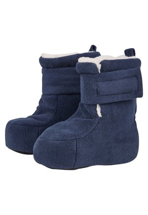 Pair of navy blue fleece boot slippers with white plush lining and adjustable Velcro straps on a white background.