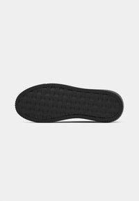 Zwarte rubberen zool met een gestructureerd oppervlak dat een rasterpatroon en verhoogde randen voor grip heeft. Afgeronde teen en achterkant.