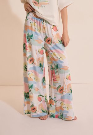 Losse wijde broek met elastische tailleband met kleurrijke tropische fruit- en palmboomprint op een witte achtergrond.
