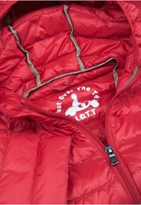 Interior de chaqueta acolchada roja con textura de acolchado, forro en contraste color marrón claro y un logo blanco con un personaje de dibujos animados. Con cremallera frontal.