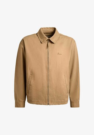 Világosbarna cipzáros dzseki hegyes gallérral, két elülső oldalzsebbel és kis logóval a bal mellrészen.