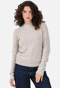 Beige knit sweater with a ribbed neckline and cuffs, featuring a soft texture and long sleeves, paired with dark blue jeans.