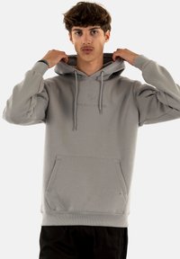 Felpa grigia chiara realizzata in tessuto morbido, con tasca a marsupio, cordoncino e logo in rilievo sul petto. Polsini e orlo a coste.