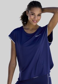 Tums zils sporta krekls ar īsām piedurknēm, brīvs piegriezums un balti akcenti. Priekšpusē redzams logo "CPNHN". Gluda, viegla auduma. 