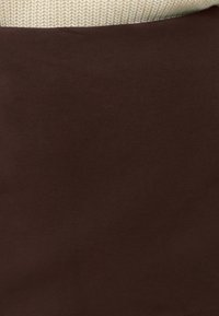 Gros plan d'échantillons de tissu avec un textile brun foncé lisse sur un textile tricoté crème texturé.