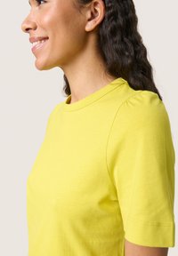 Bright yellow T-shirt in soft fabric, featuring a round neckline and short sleeves with gathered detailing at the shoulder seam.