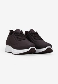Dark brown athletic shoes with a textured upper, lace-up design, and white sole. Features a padded collar and flexible material.