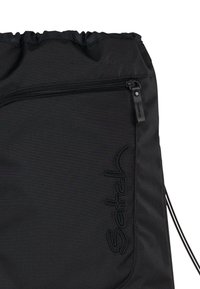 Black drawstring bag featuring a zipper pocket and embossed logo. Made of textured fabric with a smooth finish. Compact and functional design.