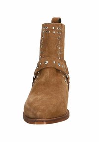 Brown suede ankle boot with silver stud accents, a strap around the midsection, and a rounded toe. Solid brown sole with slight heel.