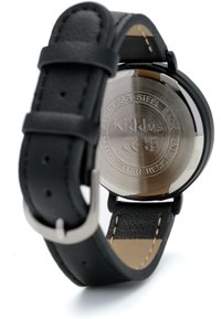 Montre avec bracelet en cuir noir et dos en acier inoxydable, avec des détails gravés et une finition lisse et brillante.