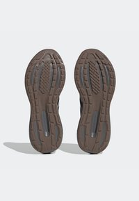 Czarne buty sportowe z teksturowaną gumową podeszwą z falistym wzorem, elementami amortyzującymi oraz detalem z logo na śródpodeszwie.