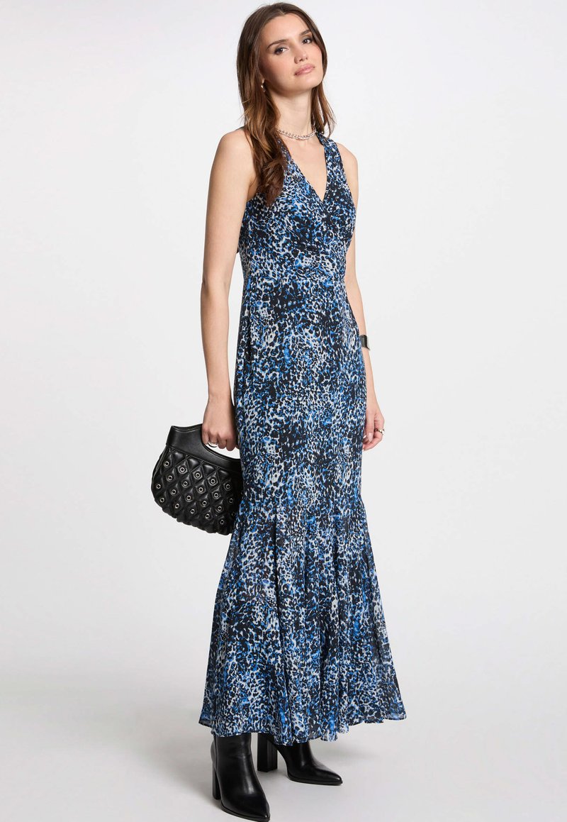 Robe maxi à motif léopard bleu avec un décolleté V plongeant, une jupe évasée et un tissu texturé. Associée à un sac à main noir matelassé.