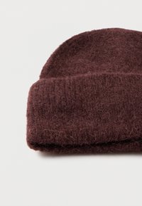 Burgundy knit beanie made of soft wool blend, featuring a folded cuff and fuzzy texture. Round top with no additional embellishments.