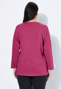 Bluzka z długim rękawem w jasnym magenta, o luźnym fasonie i gładkiej fakturze, z okrągłym dekoltem i podszytym brzegiem.