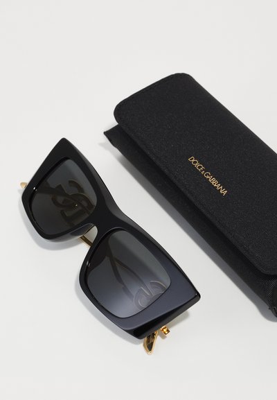 Black rectangular sunglasses with gray lenses, featuring a gold accent. Accompanied by a black case with gold branding.