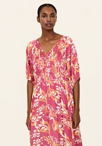 Rochie maxi roz cu mâneci scurte și lărgite, decolteu în V, detalii pliate, cu modele botanice galbene și albe. Material ușor.