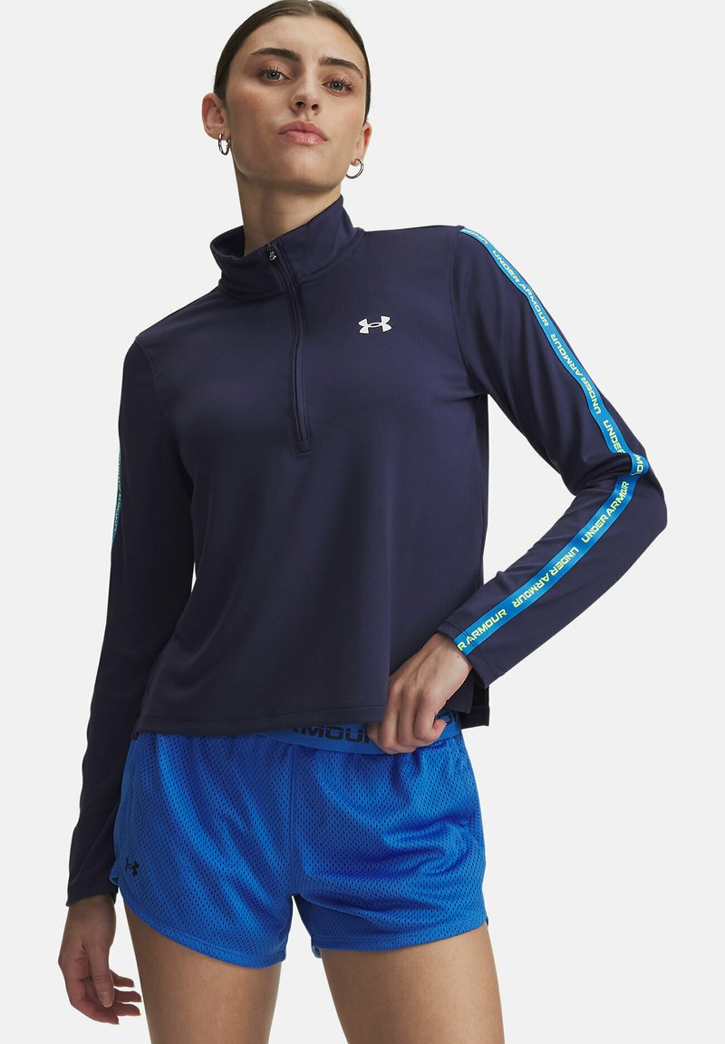 Navy long-sleeve top with quarter zip, featuring light blue shoulder panel with "Under Armour" text. Blue mesh shorts with elastic waistband.