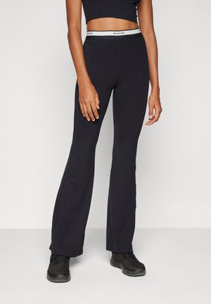 Leggings negras acampanadas con una cintura alta que presenta una banda de acento gris. Textura suave y diseño ceñido, ideal para ropa de deporte.