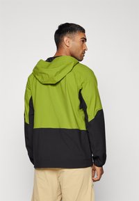 Zielona i czarna kurtka z kapturem z kontrastowym wzorem w blokach kolorystycznych, gładką strukturą i rękawami z otworami na kciuki. Materiał jest lekki i przewiewny.