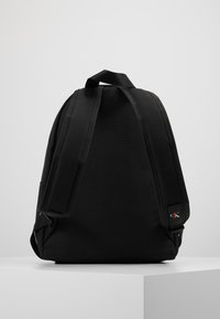 Czarny plecak z materiału, z wyściełanymi ramiączkami, uchwytem na górze i małym akcentem logo. Gładka tekstura i prosty, minimalistyczny design.