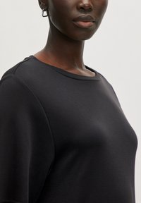 Zwarte top met korte mouwen, gemaakt van gladde, rekbare stof. Heeft een ronde halslijn en schoudernaden, wat zorgt voor een comfortabele pasvorm.