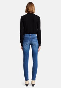 Dark sweater, light blue high-waisted jeans, slim fit, with a slight fade. Heels in a cream color with a square toe and block heel.