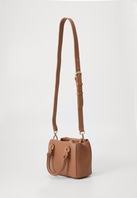 Koori pruunist tehisnahast käekott, millel on struktureeritud kuju, topelt ülemised käepidemed ja eemaldatav reguleeritav rihm. Kuldset tooni riistvara aktsendid.