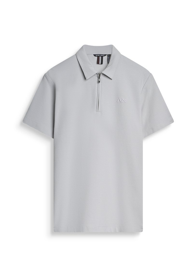Polo grigio con collo a zip, maniche corte e un motivo testurizzato. Presenta un logo discreto sul petto. Realizzato in tessuto traspirante.