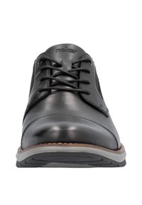 Zapatos de cuero negro con cordones, punta redondeada, lados texturizados y un acento marrón claro alrededor de la suela. Acabado suave con suela de goma duradera.