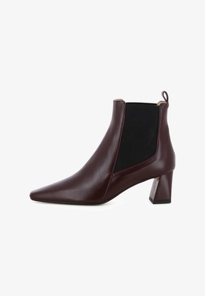 Stivaletti alla caviglia in pelle bordeaux con punta affilata, pannelli laterali elastici e tacco geometrico a blocco. Texture liscia, dettagli minimali.