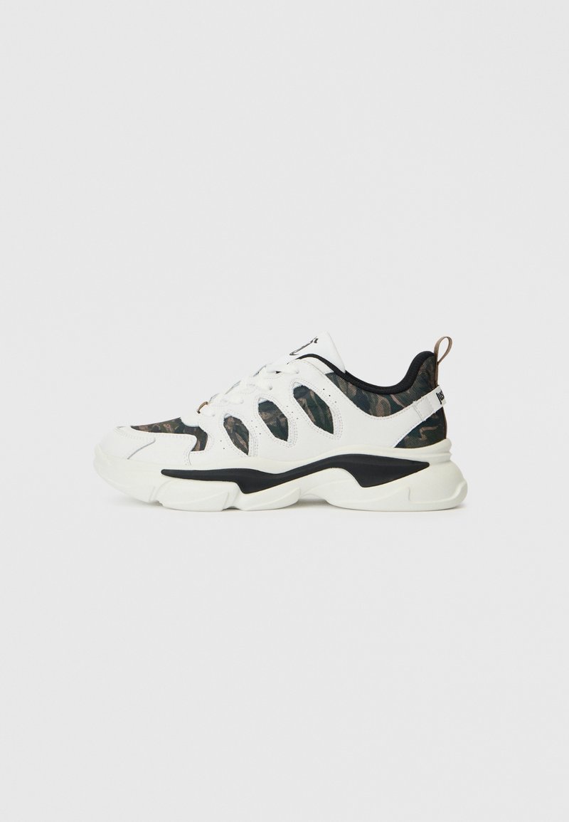 Weiße und schwarze Sneaker mit Camouflage-Stoffeinsätzen, dicker weißer Sohle, Schnürverschluss vorne und Zuglasche an der Ferse.