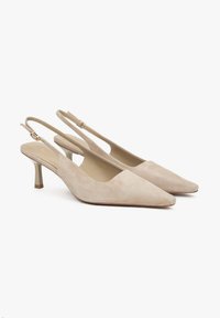 Beige suède slingbackhakken met een spitse neus, slanke hak en enkelbandje. Gladde textuur met een goudkleurig accent op de hak.