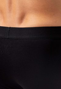 Materiale nero elastico che forma una fascia in vita aderente, mostrando una trama con una finitura liscia, che mette in risalto i contorni del corpo.