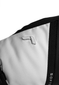Black and white soft shell fabric with sewn textured accents, featuring a silver metallic logo on the upper left corner.