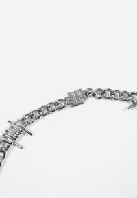 Bracciale in argento con maglie intrecciate, elementi testurizzati che ricordano viti e un dettaglio distintivo della chiusura.