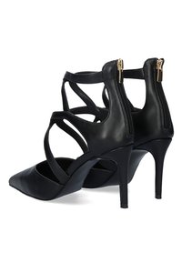 Tacones de cuero negros con punta afilada y tacón alto y esbelto. Presentan tiras entrelazadas y cierre de cremallera en la parte trasera.