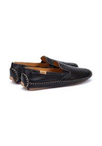 Zapatos negros de piel sin cordones con diseño perforado, costuras en contraste y un interior color marrón claro. Suela plana y acentos decorativos en los bordes.