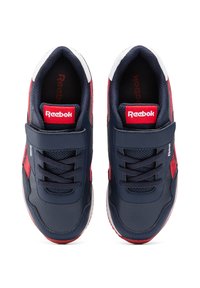 Zapatillas deportivas azul marino con acentos rojos, que cuentan con una correa de velcro, secciones de malla y suelas de goma. Material sintético texturizado.