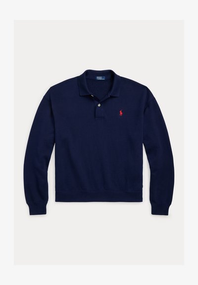 Tumesinine pika varrukaga polosärk kraega, kahe nupuga klapiga, soonikkoes mansettide ja äärega ning väike punane tikitud logo rinnal.