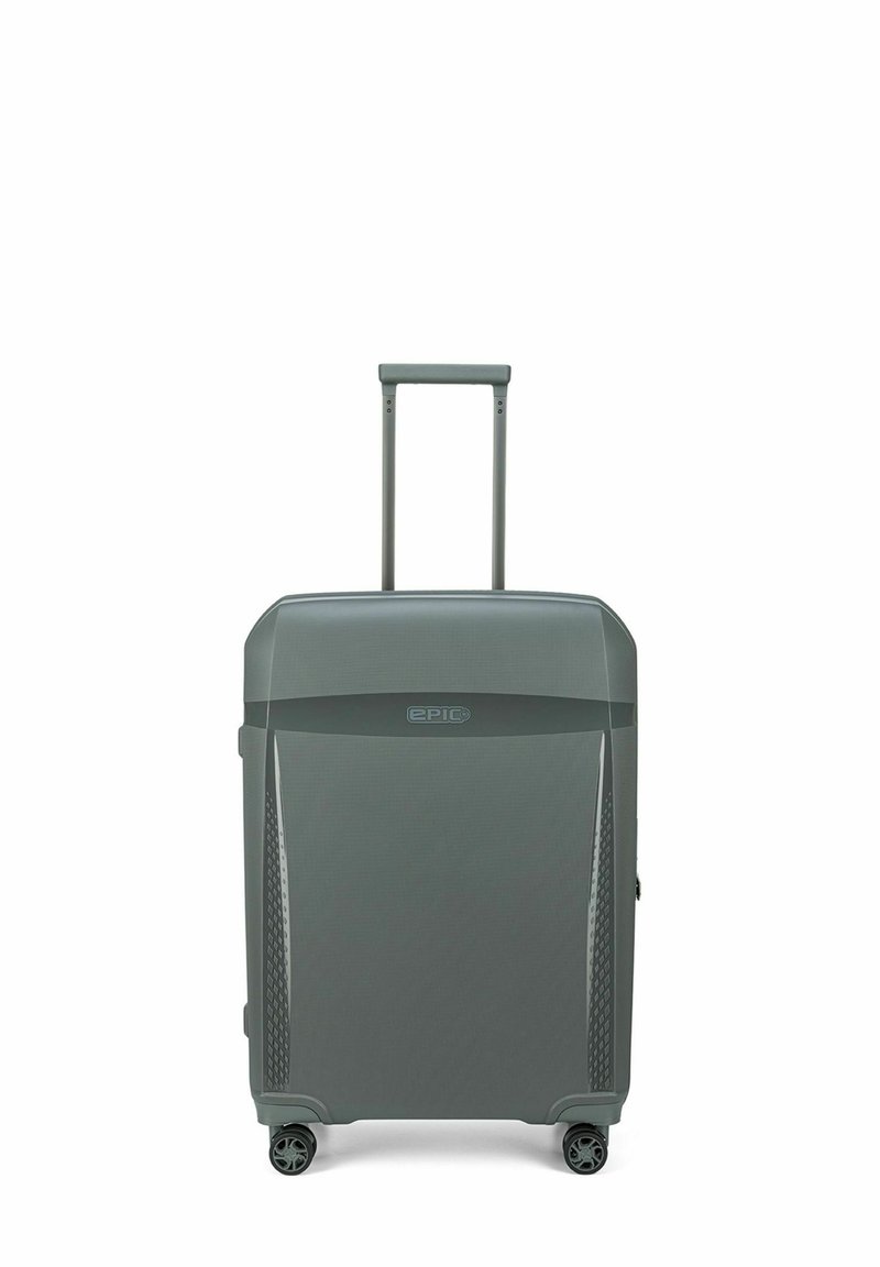 Valise rigide grise avec un motif texturé, poignée rétractable et quatre roulettes pivotantes pour une mobilité optimale. Présente une marque sur le devant.